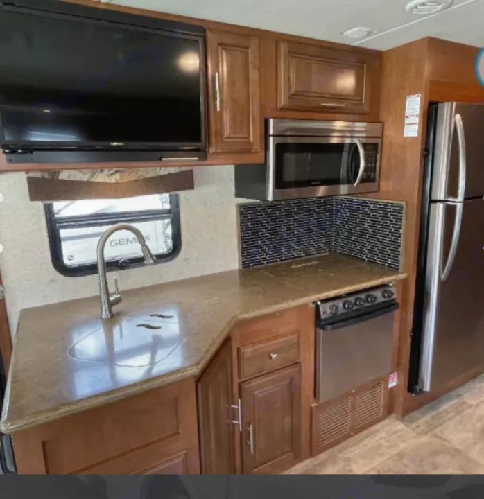 Explore this modern RV rental kitchen. Features stainless steel microwave, fridge, stove, sink, ample counter space & TV.. Georgetown XL 2015