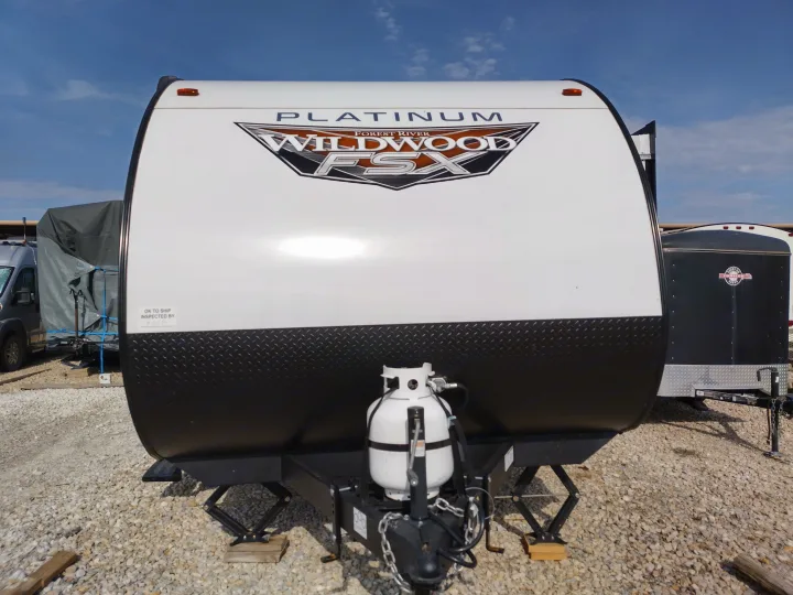 Explore this white and black travel trailer, a great option for your next RV rental. Shows the front with propane tank on a gravel lot.. Forest River Other 2022