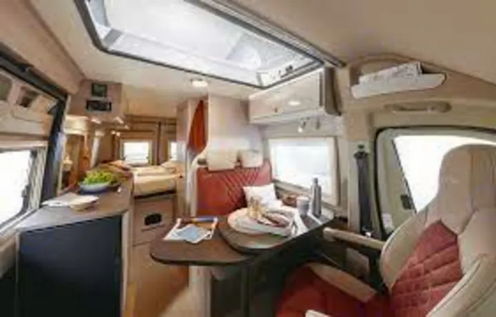 Spacious RV rental interior with bright skylight, showing dining area, kitchen counter, and a rear bedroom. Ideal for comfortable road trips.. Bürstner Campeo 600 2023