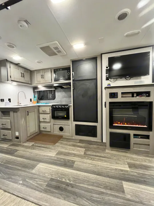 Spacious, modern RV rental interior featuring a fully-equipped kitchen, entertainment center with TV, and cozy fireplace.. Heartland RVs Mallard 2021