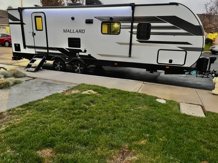 This white "Mallard" travel trailer is an ideal home on wheels for your next RV rental adventure, lights on, steps out.. Heartland RVs Mallard 2021