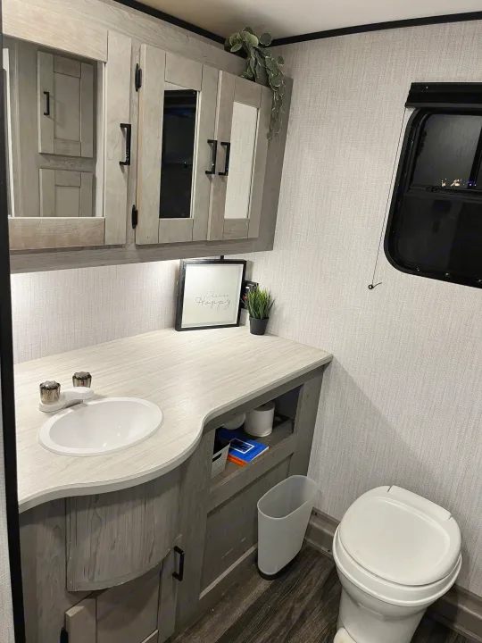 Step inside this cozy RV rental's modern bathroom, featuring a wood-look vanity with sink, mirror, and toilet.. Heartland RVs Mallard 2021