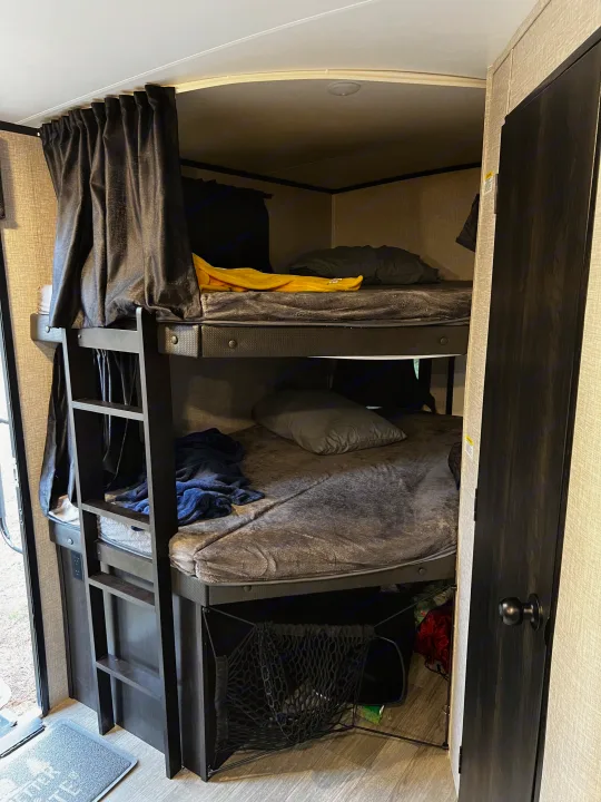 RV rental bunk beds: cozy sleeping area with privacy curtains, ladder & storage net for comfort.. Jayco White Hawk 2022