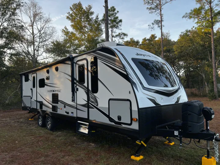 Experience nature with this Jayco White Hawk travel trailer rv rental. Parked among trees, ready for adventure.. Jayco White Hawk 2022