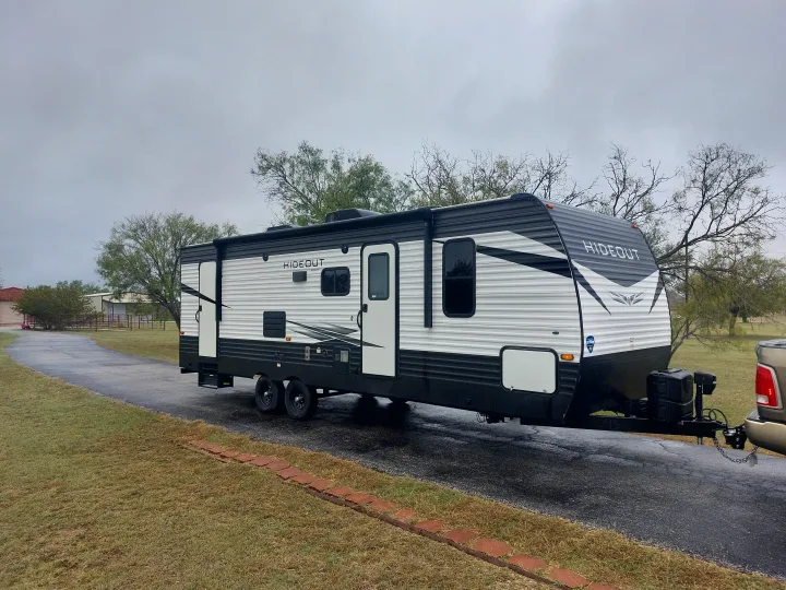 Black and white 'Hideout' RV rental: A travel trailer parked on a paved driveway, ready for adventure.. Keystone RV Hideout 2021
