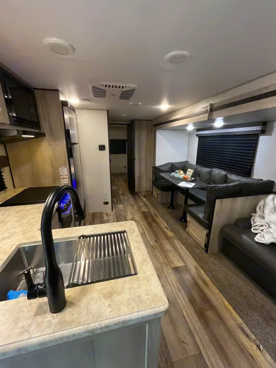 Inside a modern rv rental: kitchen with large sink, comfortable dinette living area, and ceiling AC vents visible.. KZ Connect 2021