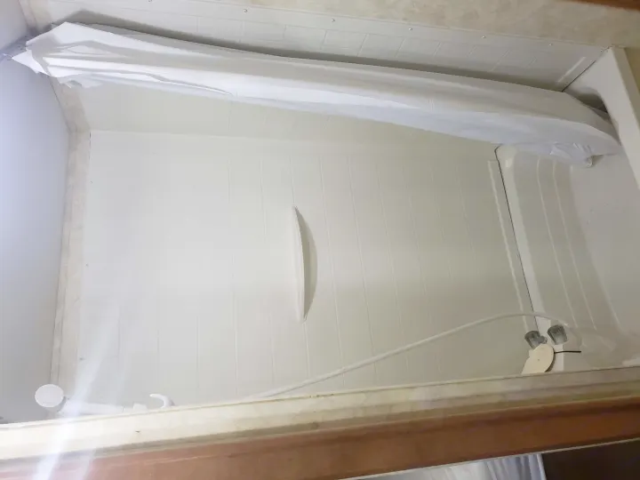RV rental compact shower: white molded tub, curtain, flexible shower head, and dual faucets visible.. Coachmen Apex 2012