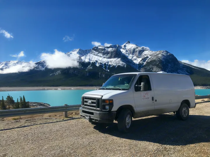 White van, perfect for an rv rental adventure, parked by a stunning turquoise lake & snow-capped mountains.. Ford Econoline 2012
