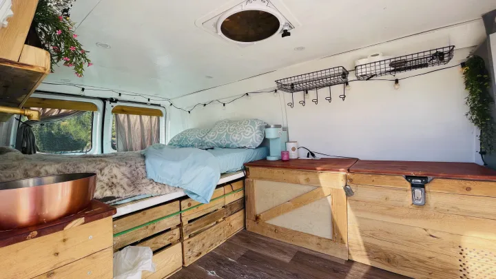 Explore the cozy rv rental interior: a comfortable bed, custom wooden storage, and thoughtful amenities for your journey.. Ford Econoline 2012