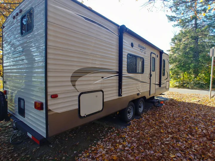 Spacious travel trailer RV rental parked at an autumn campsite, surrounded by fallen leaves, ready for adventure.. Keystone RV Hideout LHS 2017