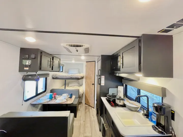Spacious RV rental interior with full kitchen, dining area, and bunk beds, perfect for family travel.. Keystone RV Springdale 2022