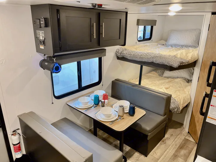 RV rental interior featuring a bright dinette area set for dining and comfy bunk beds, showcasing a compact living space.. Keystone RV Springdale 2022