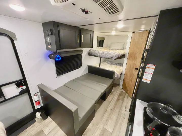 This RV rental interior features cozy bunk beds, a convertible sofa, and a compact kitchen for comfortable travel.. Keystone RV Springdale 2022