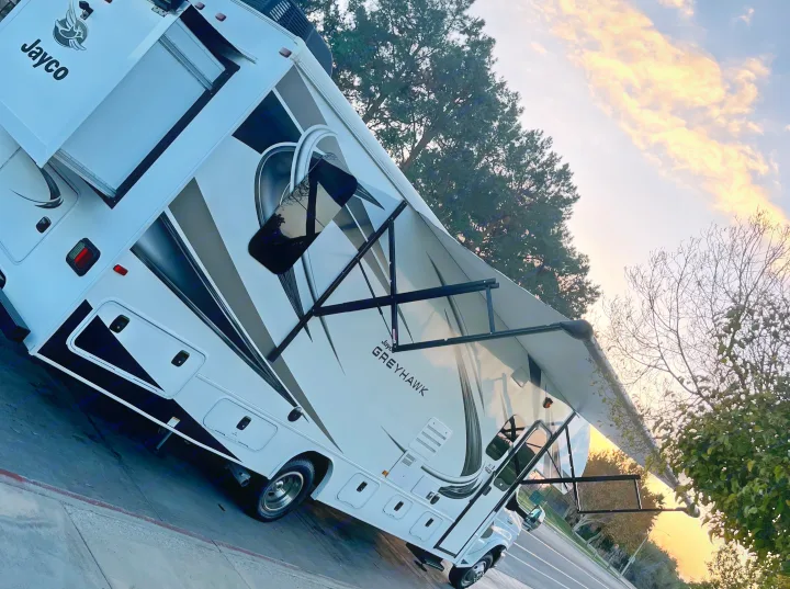 A white & grey Jayco Greyhawk RV rental with an extended awning, parked at sunset for your next adventure.. Jayco Greyhawk 2020
