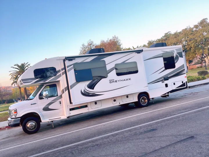 A white Jayco Greyhawk RV rental, a Class C motorhome, is parked outdoors under a blue sky, ready for adventure.. Jayco Greyhawk 2020