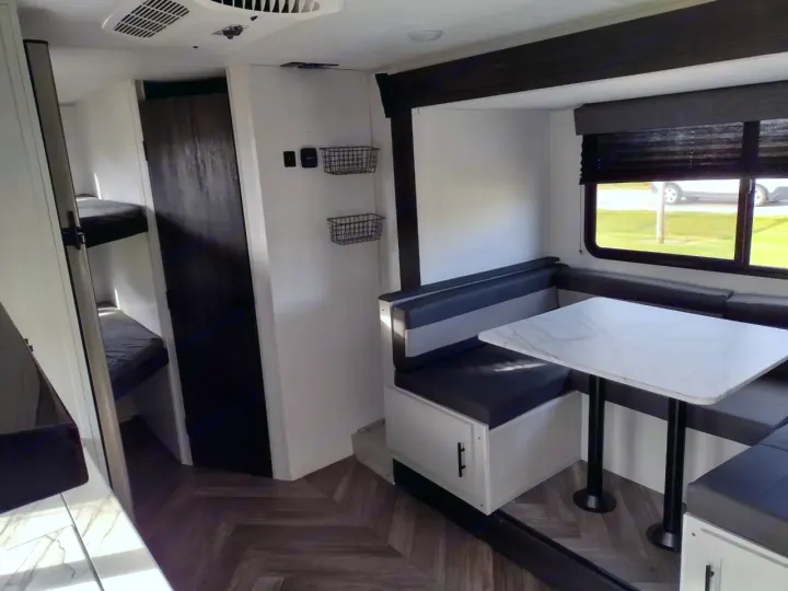 This inviting RV rental interior features a cozy dining booth, twin bunk beds, and a modern design. Ideal for your next road trip!. Forest River Wildwood FSX 2022