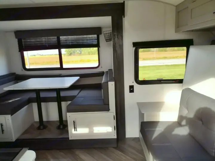 Spacious RV rental interior featuring a dinette, comfortable seating, and large windows with scenic outdoor views. Ideal for travel.. Forest River Wildwood FSX 2022