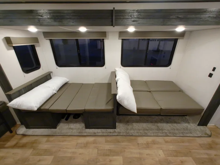 Spacious RV rental interior with two gray convertible sofa beds under windows, providing flexible seating & sleeping.. Keystone RV Hideout 2022