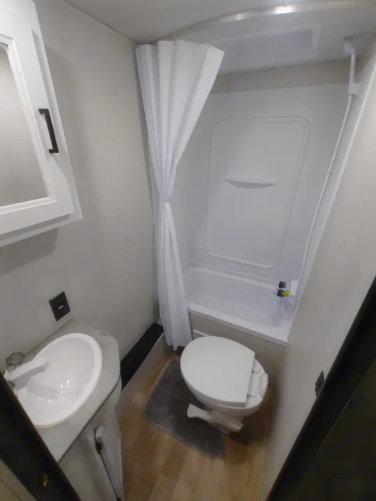 A compact and functional RV rental bathroom featuring a sink, toilet, and shower/tub.. Keystone RV Hideout 2022