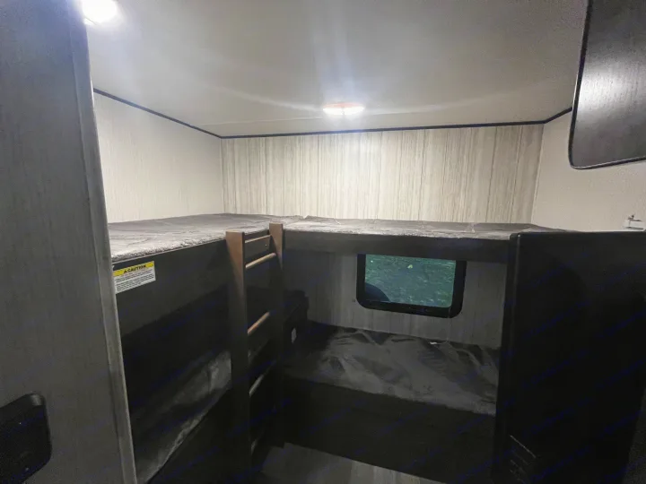 RV rental interior: Comfortable dark bunk beds (two upper, two lower), a window, and ceiling lights.. Heartland RVs Pioneer 2020
