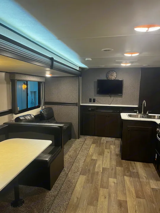 Spacious RV rental interior featuring a comfortable dinette, sofa, TV, and modern kitchen. Ideal for road trip comfort.. Heartland RVs Pioneer 2020