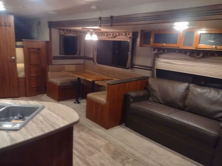 Inside this RV rental, discover a functional living area: kitchen counter, dining booth, comfy sofa, and bunk beds.. Heartland Trail Runner 2016