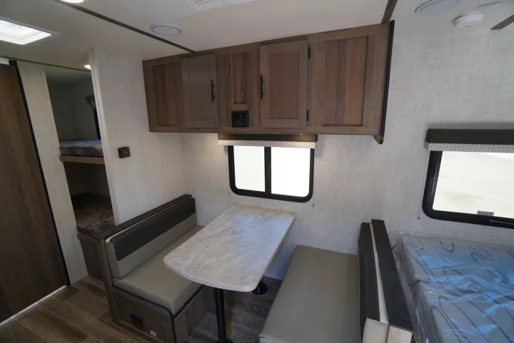 Inside an RV rental: a cozy dinette with bunk beds and overhead storage, perfect for family adventures.. Gulf Stream Trailmaster 2022