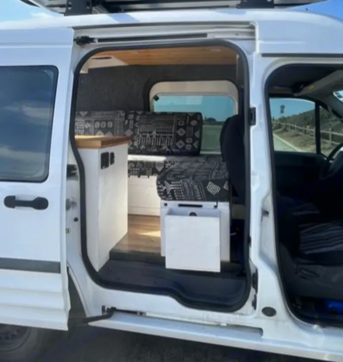 View inside an rv rental camper van, featuring a custom interior with patterned cushions and wood accents.. Ford Transit 2012