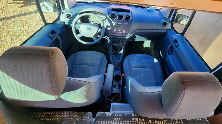 RV rental: Interior view of a Ford van's front cabin, showing driver/passenger seats, dashboard, and steering wheel.. Ford Transit 2012