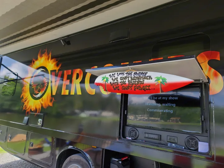 This custom RV rental boasts bold 'Overcomes' graphics and an outdoor entertainment setup with a TV and speakers, perfect for mobile leisure.. Jayco Precept 2020