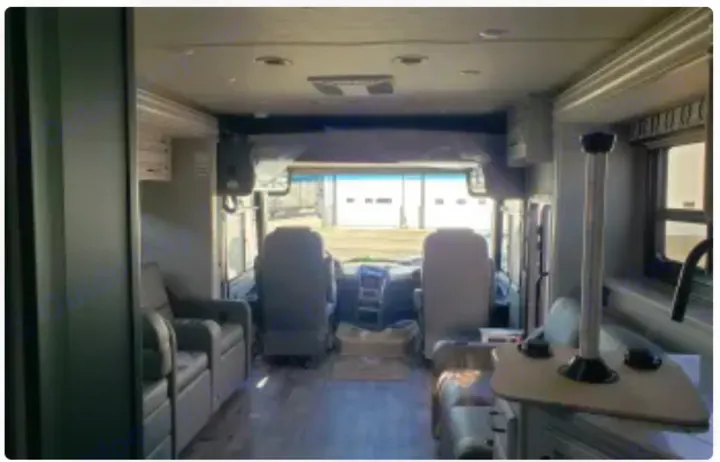 Spacious RV rental interior: cockpit with swivel chairs, left recliners, right kitchen counter, and wood-look flooring. Natural light.. Jayco Precept 2020