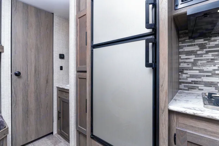 RV rental: Modern interior with kitchen, fridge, stovetop, and tiled backsplash. An adjacent door suggests a private space.. Gulf Stream Kingsport 2022