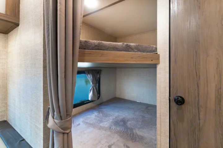 RV rental: See a cozy bunk bed area with a soft top bunk, lower sleeping space, and a window overlooking water.. Gulf Stream Kingsport 2022