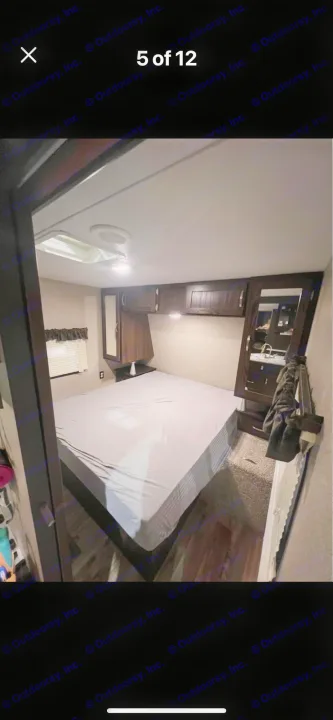 RV rental: Bedroom interior with bed, overhead cabinets, window, and compact vanity area on the right.. Keystone RV Springdale 2019