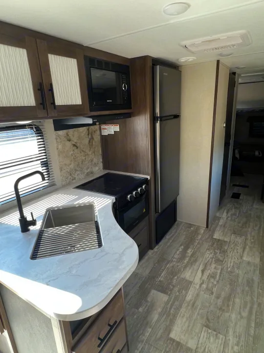 Step inside this modern RV rental kitchen, featuring a sink, microwave, stove, fridge, and ample storage for your travels.. Avenger Avenger Trailer 2021