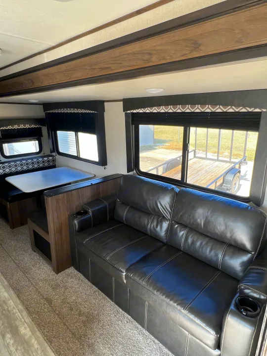 Spacious RV rental interior with comfortable black leather sofa, dinette, and large windows. Enjoy your journey!. Avenger Avenger Trailer 2021