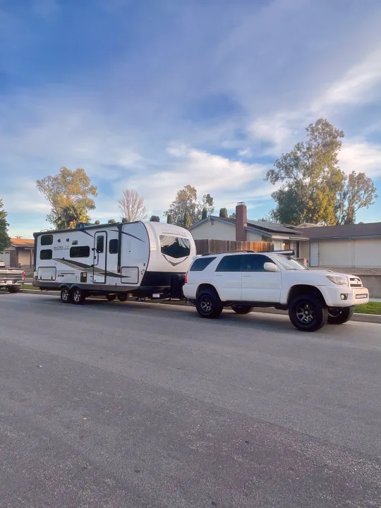 White SUV towing a Microlite travel trailer (an RV rental option) parked on a street.. Flagstaff Microlite 2023