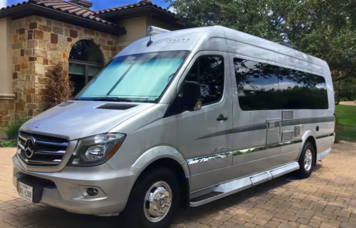 This silver Mercedes-Benz Sprinter RV, perfect for an **RV rental**, is parked on a paved driveway.. Winnebago Era 2016