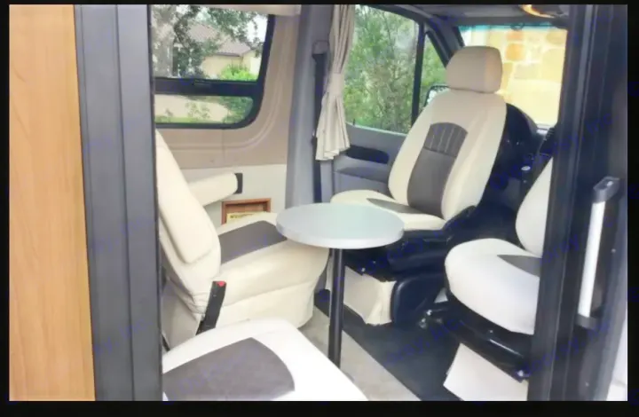 Inside an RV rental: swivel cream and brown captain's chairs surround a small table, creating a cozy living space for travel.. Winnebago Era 2016