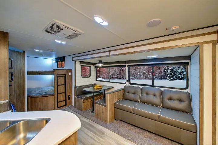 Cozy RV rental interior features a living area, dinette, kitchen, and bunk beds. Enjoy snowy views on your journey.. Heartland Pioneer 2022