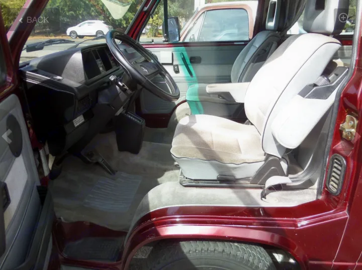 Inside this RV rental: view of the driver's cabin with steering wheel and front seats.. Volkswagen Westfalia 1990