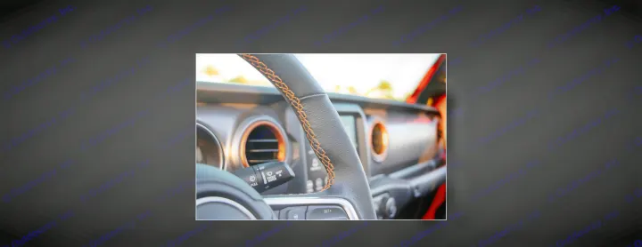 Adventure-ready RV rental interior: black steering wheel with orange stitching, and highlighted dashboard accents.. Jeep Gladiator 2022