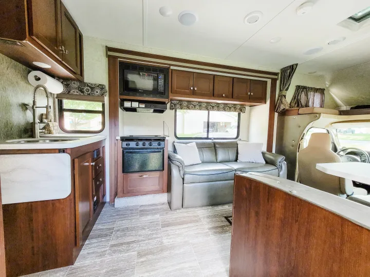 Spacious RV rental interior with kitchen, living area, and amenities, featuring wood cabinetry and light flooring.. Forest River Sunseeker LE 2018