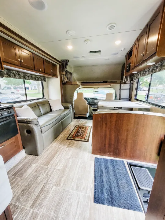 Clean, spacious RV rental interior featuring a cozy sofa, kitchen, dinette, and cockpit. Perfect for road trips.. Forest River Sunseeker LE 2018