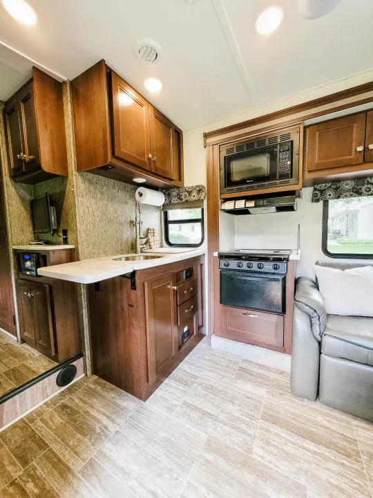 Clean, functional RV rental kitchen and living area: microwave, stove, sink, ample cabinets, and cozy seating.. Forest River Sunseeker LE 2018