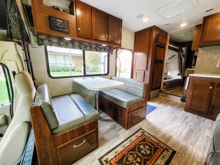 This **rv rental** interior showcases a dining booth, kitchen, overhead storage, and a bunk bed area, offering ample living space.. Forest River Sunseeker LE 2018
