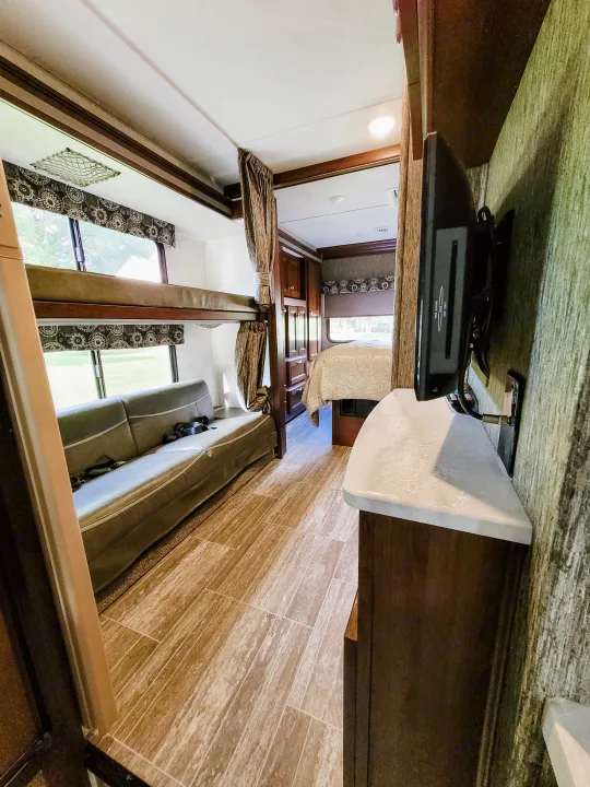 Spacious RV rental interior with bunk beds, sofa, and main bedroom. Perfect for comfortable travel and lodging.. Forest River Sunseeker LE 2018