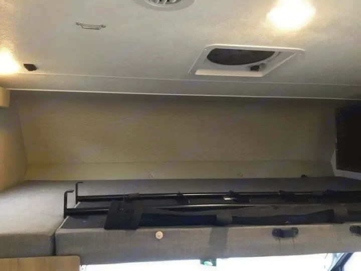 Overhead bunk with safety rail and ceiling details inside an RV rental, featuring a vent and lighting.. Forest River Coachmen Freelander Premier 2022