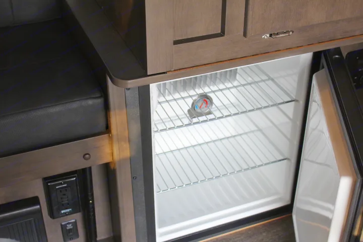 An open, clean mini-fridge with wire shelves and a temperature gauge inside an RV rental, ready for your trip's food.. Forest River Rockwood ESP 2021
