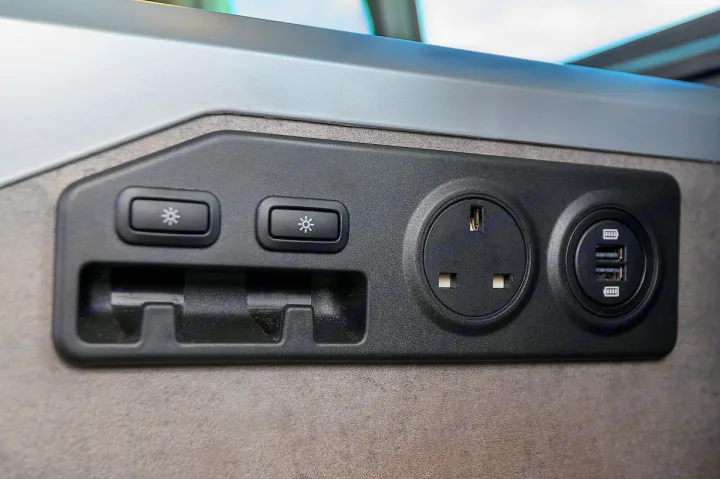 RV rental: close-up of an interior panel with light controls, a UK power outlet, dual USB charging ports, and a storage slot.. Volkswagen California Ocean 2024
